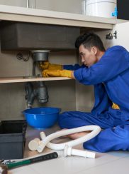 Checking drain Young Vietnamese plumber checking drain in kitchen