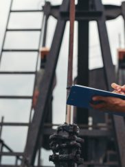 Workers standing and checking beside working oil pumps. Workers standing and checking beside working oil pumps.