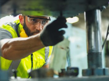 Close up hand industrial industrial plant with a tablet in hand, Engineer looking of working at industrial machinery setup in factory.